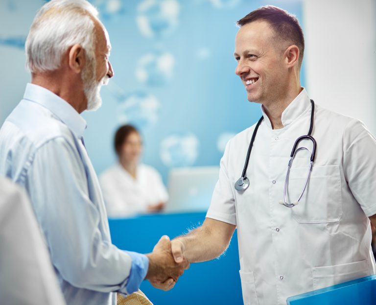 Happy doctor handshaking with senior patient at the hospital